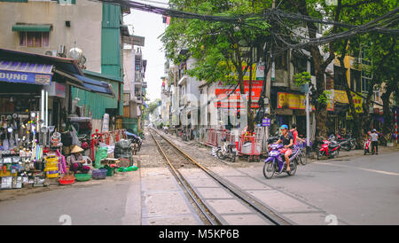 Une voie de chemin de fer passe par les maisons et des magasins d'une rue de Hanoi, Vietnam Banque D'Images