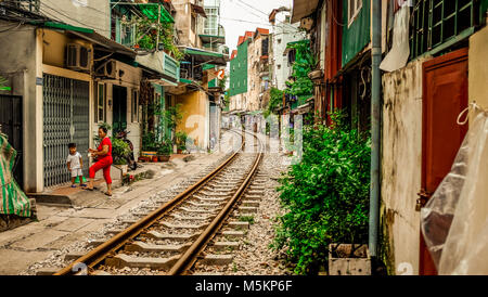 Une voie de chemin de fer passe par les maisons et des magasins d'une rue de Hanoi, Vietnam Banque D'Images