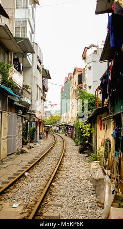 Une voie de chemin de fer passe par les maisons et des magasins d'une rue de Hanoi, Vietnam Banque D'Images