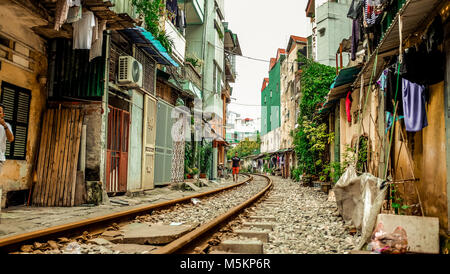 Une voie de chemin de fer passe par les maisons et des magasins d'une rue de Hanoi, Vietnam Banque D'Images