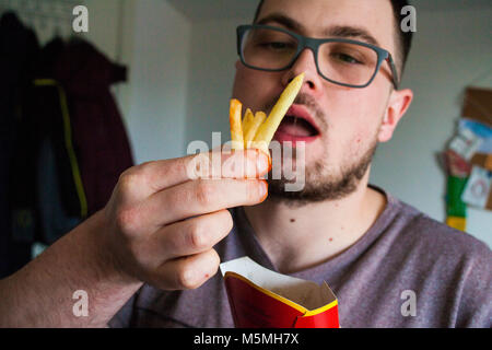 L'homme de manger les frites, les pommes de terre, chip, malsaines junk fast food Banque D'Images
