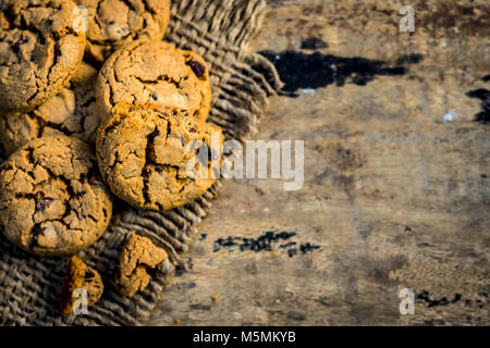 Fraîchement fait maison biscuits aux brisures de chocolat sur fond de jute. Banque D'Images
