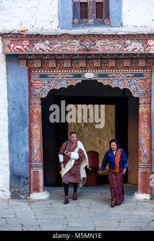 Trongsa, Bhoutan. L'homme et de la femme en passant par l'entrée dans la première cour de la Trongsa Dzong (Monastery-Fortress), vue de l'intérieur de la Cour. Banque D'Images