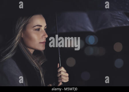 Portrait of a woman standing under authentique parapluie nuit pluvieuse, photo conceptuelle de solitude et de tristesse Banque D'Images