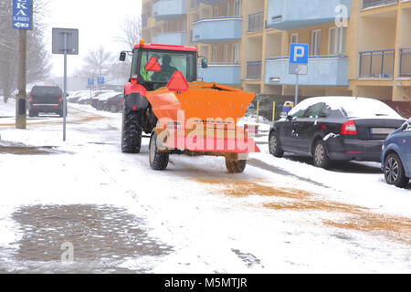 Tracteur avec une remorque automatique pour répandre du sable sur les routes. Banque D'Images