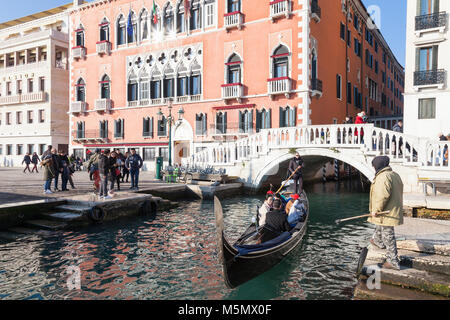 À propos de gondole pour débarquer les touristes en face de l'hôtel Danieli, Riva degli Schiavoni, Castello, Venise, Italie avec un homme aux prises avec une attente ho Banque D'Images