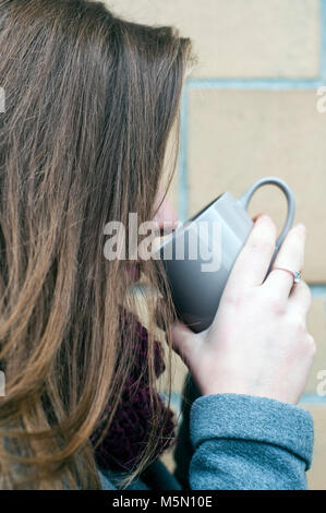 Brunette jeune femme à boire une tasse de Banque D'Images