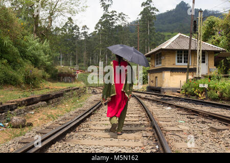 Femme portant sari traditionnel parapluie noir et marcher sur des rails de chemin de fer au Sri Lanka. Banque D'Images