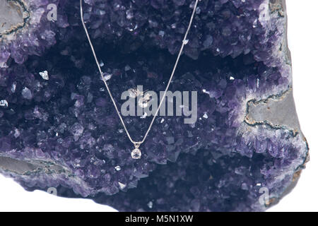 Pendentif cristal sur chaîne argent présentés sur l'améthyste géode isolé sur fond blanc Banque D'Images