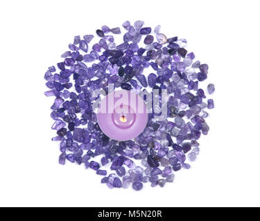 Lavender tea light amethyst bougie entouré par les petites puces tumbled isolé sur fond blanc Banque D'Images