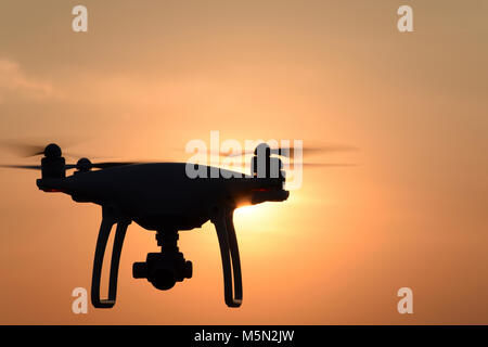 Silhouette Quadrocopters contre l'arrière-plan de la coucher du soleil. Drones volant dans le ciel du soir. Banque D'Images