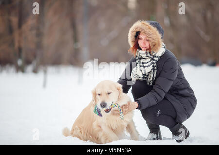 Photo de femme accroupie à côté de labrador avec jouet dans les dents dans winter park Banque D'Images