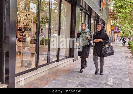 Kashan, Iran - avril 25, 2017 : deux femmes iraniennes dans un hijab sont à pied le long de la rue près d'un magasin avec des sacs et de sourire. Banque D'Images