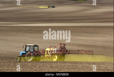 La pulvérisation de produits chimiques le tracteur sur le terrain. le tracteur l'arrosage de pesticides contre les insectes sur le domaine agricole. Banque D'Images