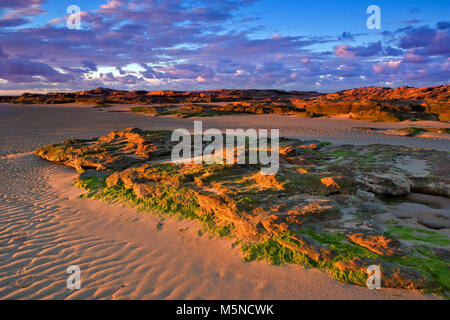 Coucher de soleil sur la craggy Roches Rouges de Hoylake Wirral, plage, en Angleterre. Banque D'Images