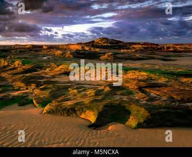 Coucher de soleil sur la craggy Roches Rouges de Hoylake Wirral, plage, en Angleterre. Banque D'Images