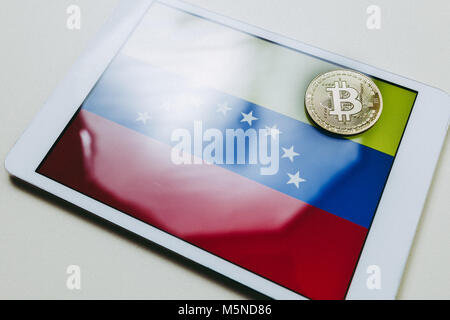 Vue rapprochée d'une tablette avec le drapeau du Venezuela et d'un gold bitcoin sur elle Banque D'Images