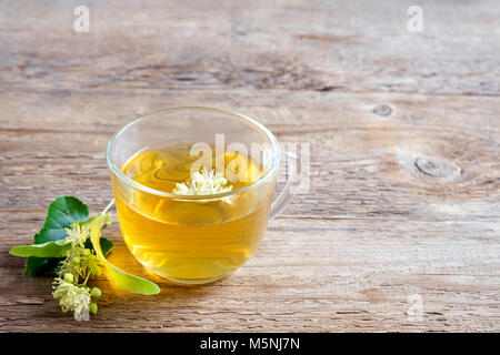 Plantes en bonne santé avec des tas de thé tilleul fleurs de tilleul frais sur fond de bois. Tasse de thé, infusion de Tilleul bio boisson. Banque D'Images