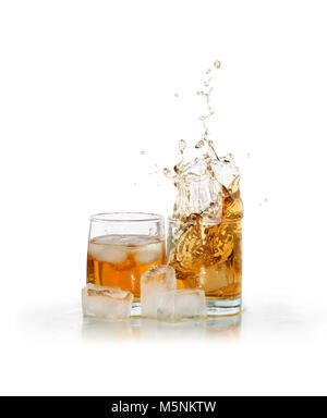 Deux verres d'éclaboussures whiskey près de cubes de glace isolé sur fond blanc avec clipping path Banque D'Images