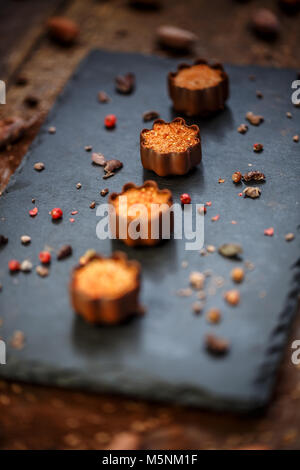 Pralines au chocolat fin rempli de massepain décorée de poivre rose concassé servi sur ardoise noire Banque D'Images