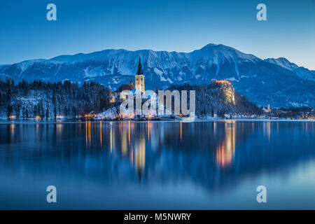 Belle vue sur le lac de Bled crépuscule avec célèbre l'île de Bled et le château historique dans l'arrière-plan pendant l'heure bleue pittoresque à l'aube en hiver, Slo Banque D'Images