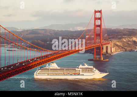 Bateau de croisière passant célèbre Golden Gate Bridge avec la skyline de San Francisco en arrière-plan dans la lumière du soir au coucher du soleil d'or, en Californie, USA Banque D'Images