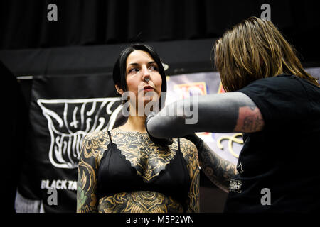 Brighton UK 25 février 2018 - Charlotte Muscat de Londres obtient un tatouage de John Fowler à la 11e Convention de Tatouage de Brighton s'est tenue dans le centre de Brighton au cours du week-end d'attirer des artistes tatoueurs du monde entier Photo prise par Simon Dack Crédit : Simon Dack/Alamy Live News Banque D'Images