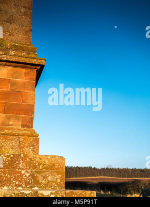 Blaikie Heugh East Lothian, Ecosse, Royaume-Uni, le 25 février 2018. Complètement clair Ciel bleu avec de faible ensoleillement le soleil qui illumine la Colline Balfour, un obélisque monument commémoratif à James Maitland Balfour, un député conservateur dans les années 1840, et le père du premier ministre Arthur Balfour, 1er comte de Balfour. La lune croissante est visible dans le ciel bleu Banque D'Images