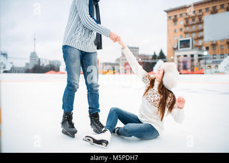 Personne mâle aide une femme à se lever, de l'amour couple sur patinoire. Hiver patinage sur open air, des loisirs actifs Banque D'Images