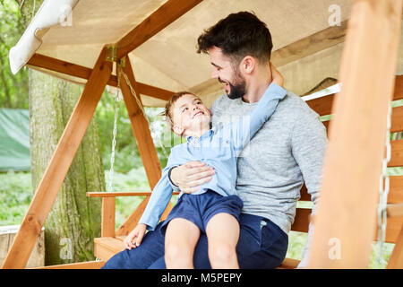 Garçon plaisante avec son père autour de la balançoire dans le jardin Banque D'Images