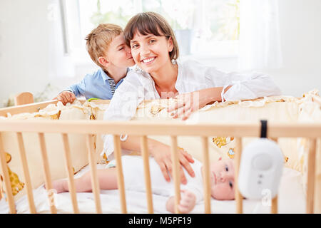 Petit garçon embrasse sa mère au lit avec le bébé nouveau-né Banque D'Images