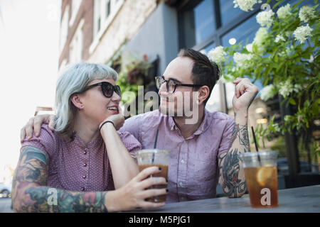 Young couple sitting in outdoor cafe boire thé glace Banque D'Images