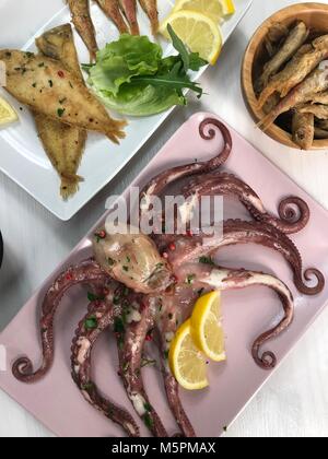 Le poisson frit,riz avec moules et poulpes sur lave avec du citron et de la salade. Banque D'Images