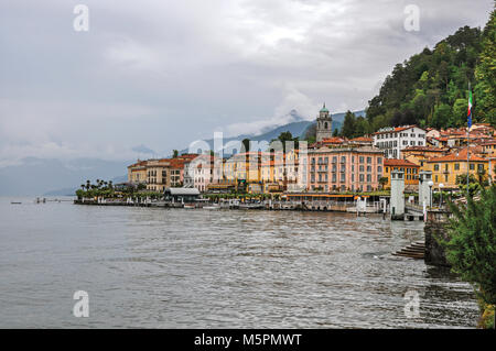 Vue sur le lac de Côme en journée nuageuse avec les bâtiments de Bellagio, un charmant village touristique entre le lac et les montagnes des Alpes. Banque D'Images