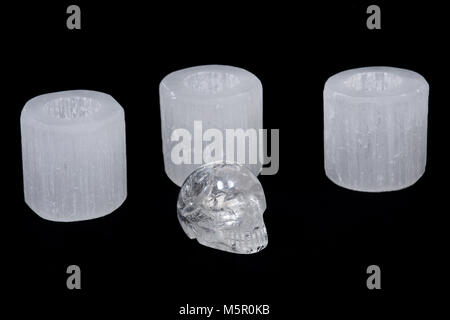 Sélénite blanc lumignon vérin supports avec crâne quartz clair sur fond noir Banque D'Images