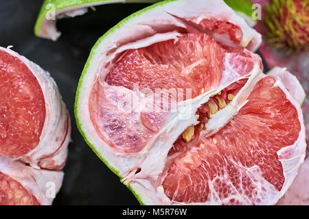 Tranches de pomelo juteux sur la plaque noire sur la table rouge. Vue de dessus Gros plan photo horizontale. Banque D'Images