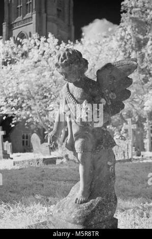 Photo infrarouge d'un chérubin en pierre dans le cimetière de St Marie la Vierge, l'église, près de Huish Episcopi Langport à Somerset, Angleterre Banque D'Images