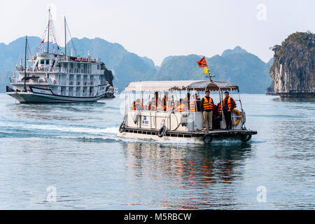 Les touristes portant des gilets orange sont prises à partir de leur bateau de croisière dans une soumission à l'AUC Van village flottant, Halong Bay, Vietnam Banque D'Images