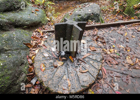 Ancienne meule utilisée pour la rectification. Un support pour le tenir a été mis en place dans le chemin d'un ruisseau et alimenté par l'écoulement de l'eau. Banque D'Images