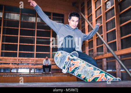 Un jeune skateur est d'effectuer un tour sur roulettes dans une piscine skate hall. Banque D'Images