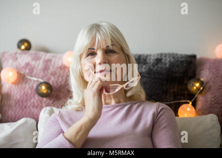 Portrait avant de la haute dame holding glasses dans son appartement Banque D'Images