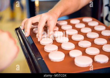 Met la main macroons rose sur le plat Banque D'Images