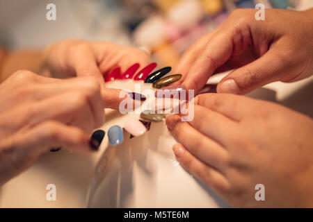 Close-up of a female clients esthéticienne et mains tenant des échantillons et choix des couleurs des ongles dans le salon de beauté. Banque D'Images