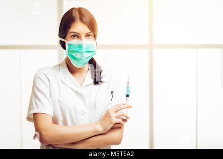 Jeune infirmière debout dans sa salle de consultation et la préparation d'une injection d'anesthésie. En regardant la caméra. Focus sélectif. Banque D'Images