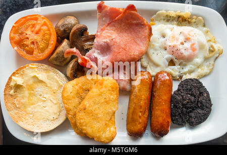 Le petit déjeuner anglais complet en œuf frit, bacon, haricots blancs, blanc muffin, boudin noir, tomates grillées, saucisses, champignons et pommes de terre rissolées Banque D'Images