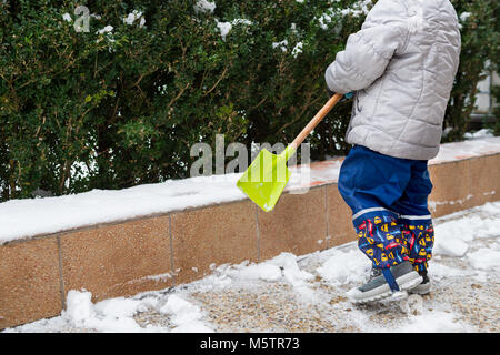 Aider l'enfant à partir de la neige du trottoir. Activités hiver famille authentique franc. Pelleter la neige concept. Banque D'Images