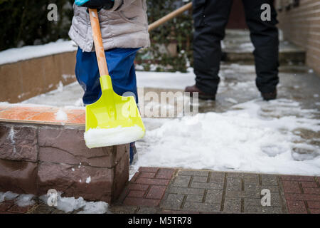 Aider les enfants de père déblayer la neige du trottoir. Activités hiver famille authentique franc. Pelleter la neige concept. Banque D'Images