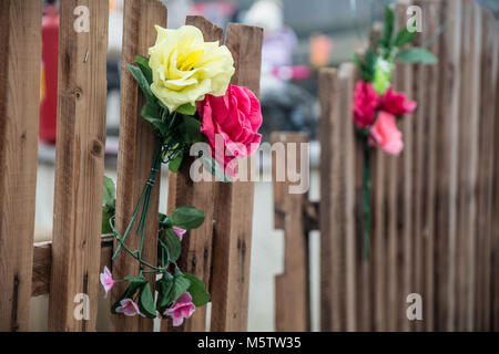 Bouquet de fleurs artificielles sur une clôture en bois Banque D'Images