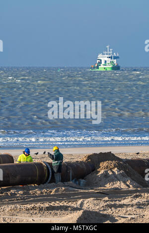 Les travailleurs de dragage les tuyaux de raccordement du pipeline au cours de reconstitution des plages de sable / Travaux publics le long de la côte belge à Ostende, Belgique Banque D'Images