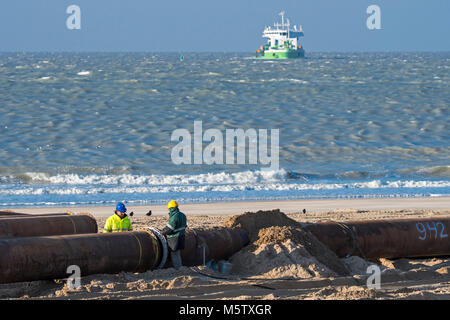 Les travailleurs de dragage les tuyaux de raccordement du pipeline au cours de reconstitution des plages de sable / Travaux publics le long de la côte belge à Ostende, Belgique Banque D'Images